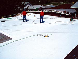 Commercial-Roofing-Companies-Nashville-TN-Tennessee-1 | Glick Roofing Systems Two workers in red shirts standing on a white roof under construction, with cords and safety lines laid out around them.