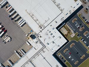 Flat-Roof-Installation-Nashville-TN-Tennessee-1 | Glick Roofing Systems Aerial view of white building rooftops and a parking lot with cars in an urban area.