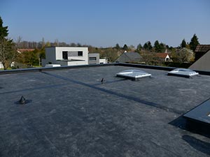 Low-Slope-Roofing-Nashville-TN-Tennessee-1 | Glick Roofing Systems Flat rooftop with two skylights on a suburban neighborhood under a clear blue sky.