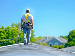 Roof-Inspection-Bowling-Green-KY-Kentucky-1 | Glick Roofing Systems Worker in safety harness walking on a residential rooftop during maintenance or inspection on a sunny day.