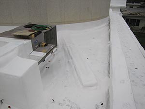 Spray-Foam-Roofing-Nashville-TN-Tennessee-1 | Glick Roofing Systems White rooftop edge with a small metal electrical box and a coiled hose on the surface.